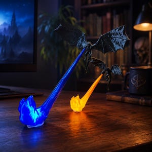May include: Two black dragon figurines in flight, each emitting a translucent stream of fire. The larger dragon projects a bright blue flame, while the smaller dragon behind it projects a vibrant orange flame. Both figures are detailed with textured wings.