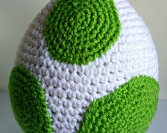 May include: A white crocheted ball with three green circles. The circles are made of crocheted yarn and are evenly spaced around the ball.
