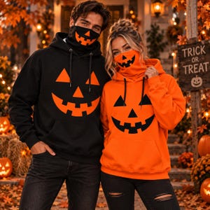 May include: A black hoodie with an orange jack-o'-lantern face and a matching black face covering, alongside an orange hoodie with a black jack-o'-lantern face and a matching orange face covering, both featuring drawstring hoods and front pockets.
