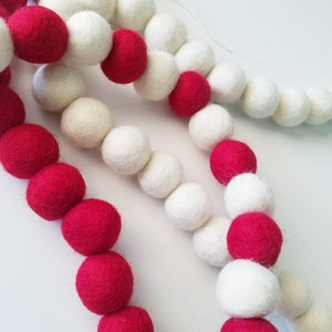 May include: A garland of red and white felt balls strung together. The garland is made of wool and is perfect for decorating for the holidays.