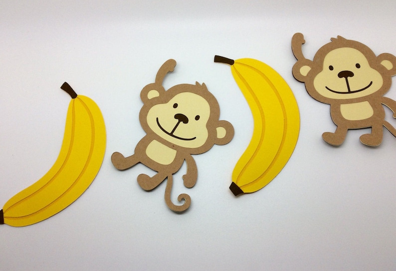 May include: Three paper cutouts of monkeys and bananas. The monkeys are brown with yellow faces and black eyes. The bananas are yellow.