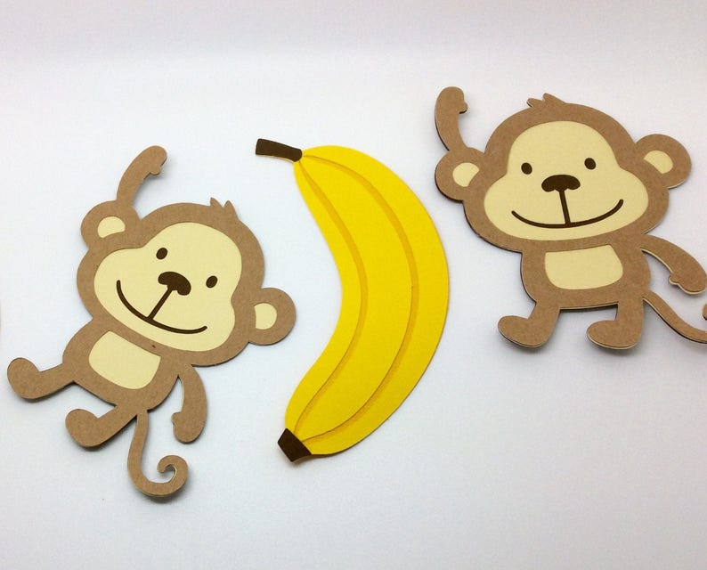 May include: Two brown paper monkey cutouts with smiling faces and a yellow paper banana cutout.