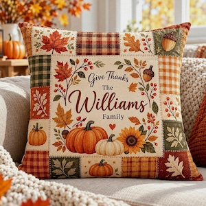 May include: A square decorative pillow featuring a patchwork-style border with plaid and gingham patterns in orange, brown, and green. The center panel displays autumn leaves, pumpkins, a sunflower, and the text Give Thanks The Williams Family.