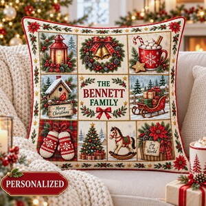 May include: A square decorative throw pillow featuring a grid of nine Christmas-themed illustrations, including a lantern, a wreath with bells, a mug of cocoa, a birdhouse, a red sleigh, mittens, a tree, a rocking horse, and a basket with poinsettias.