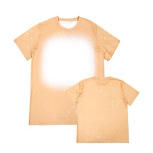 May include: Two tan t-shirts with a white splatter pattern. The t-shirt on the left has a larger white splatter pattern in the center. The t-shirt on the right has a smaller white splatter pattern.