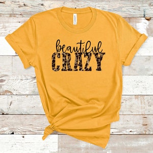 May include: A mustard yellow t-shirt with the text "beautiful crazy" printed in black with a leopard print pattern.