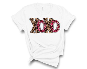 May include: White t-shirt with a graphic of the word "XOXO" in leopard print with pink accents.
