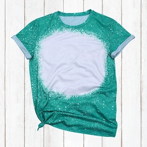 May include: A teal green t-shirt with a white circle in the center. The circle has a splatter paint effect around the edges.