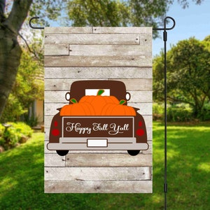 Könnte beinhalten: Ein brauner Vintage-Pickup mit einer Holzladefläche, die mit orangefarbenen Kürbissen gefüllt ist. Der LKW hat einen weißen Hintergrund mit dem Text "Happy Fall Y'all" auf der Rückseite.
