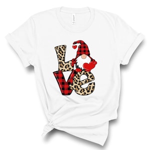 May include: White t-shirt with a red and black plaid and leopard print "LOVE" graphic featuring a gnome holding a red heart.