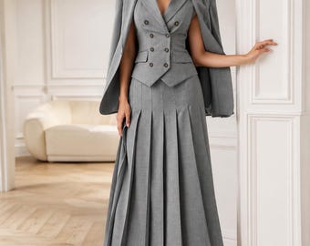 May include: A grey three-piece ensemble consisting of a sleeveless double-breasted vest with dark buttons, a matching pleated midi skirt, and a coordinating blazer draped over the shoulders. The outfit features a structured, tailored appearance.