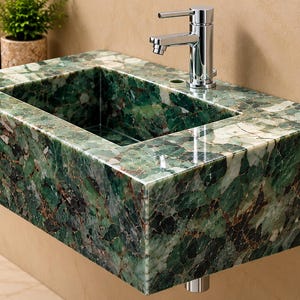 May include: A rectangular wall-mounted bathroom sink crafted from polished green stone with intricate white and dark veining. The basin features a smooth, glossy finish and is equipped with a single chrome-finished metal faucet fixture.