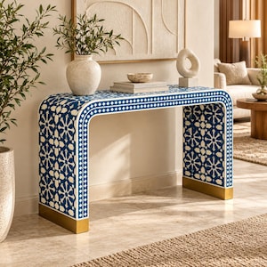 May include: A rectangular console table featuring a blue and white geometric star pattern across its surface. The table has a curved waterfall design with gold-toned metal accents at the base of each leg, providing a stable and level foundation.