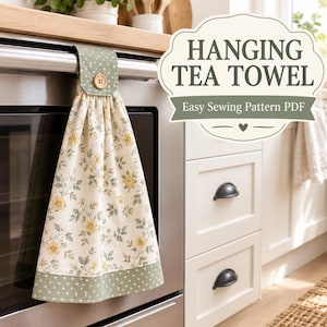 May include: A hanging tea towel with a cream background featuring a yellow floral pattern and a sage green polka dot border. The towel is secured with a sage green polka dot tab and a wooden button. Text reads HANGING TEA TOWEL Easy Sewing Pattern PDF.