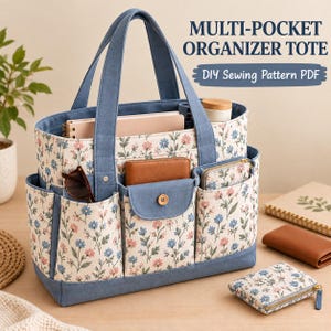 Pode incluir: Uma bolsa tote organizadora com vários bolsos em tecido creme com estampa floral azul e rosa, acentuada por acabamentos, alças e um bolso central em tecido azul sólido com fecho de botão de madeira. O texto diz MULTI-POCKET ORGANIZER TOTE.