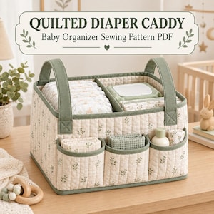 Könnte beinhalten: Ein gesteppter Windel-Organizer mit cremefarbenem und grünem Blattmuster, ausgestattet mit zwei Griffen, drei Außentaschen und Inneneinteilungen. Der Text QUILTED DIAPER CADDY Baby Organizer Sewing Pattern PDF steht über dem Stoffkorb.