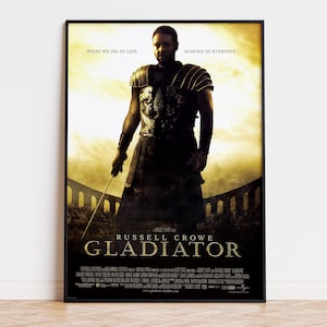 Puede incluir: Un póster de película enmarcado de Gladiator que muestra a Russell Crowe con armadura romana sosteniendo una espada. El texto dice: WHAT WE DO IN LIFE ECHOES IN ETERNITY, RUSSELL CROWE y GLADIATOR, con créditos de producción al pie.