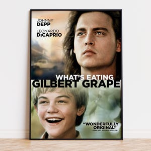 May include: A framed movie poster for What's Eating Gilbert Grape featuring portraits of Johnny Depp and Leonardo DiCaprio. The title is printed in large white letters across the center, with the text WONDERFULLY ORIGINAL in the bottom corner.