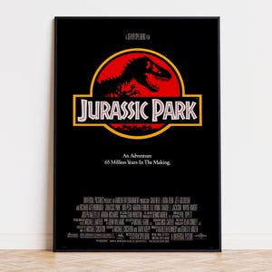 May include: A black movie poster for Jurassic Park featuring a red circle with a black dinosaur skeleton silhouette. The text reads A Steven Spielberg Film, Jurassic Park, An Adventure 65 Million Years In The Making, and production credits.