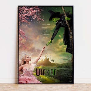 Peut inclure: Une affiche de film encadrée pour Wicked montrant une sorcière à la peau verte avec un chapeau et une cape noirs tendant la main vers une silhouette blonde en robe rose et couronne. Le texte indique Everyone deserves the chance to fly, Wicked, et November 22.