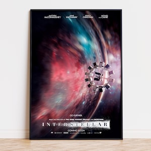 Peut inclure: Une affiche de film encadrée pour Interstellar montrant une station spatiale en rotation sur un fond de nébuleuses cosmiques rouges et bleues tourbillonnantes. Le texte inclut le titre, les noms des acteurs et le slogan Go Further en blanc.