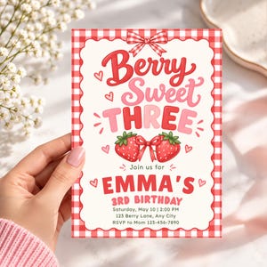 May include: A rectangular birthday invitation card with a red and white gingham border. The text reads Berry Sweet THREE, Join us for EMMA'S 3RD BIRTHDAY, Saturday, May 10, 2:00 PM, 123 Berry Lane, Any City, RSVP to Mom 123-456-7890.
