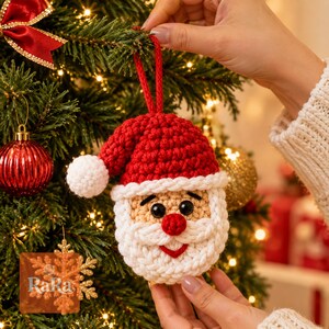 Puede incluir: Un adorno de Papá Noel tejido a ganchillo con un gorro rojo y pompón blanco, cara beige, ojos de plástico negro, nariz roja y barba blanca. El adorno incluye un lazo de hilo rojo para colgarlo y está elaborado con puntadas de hilo texturizado.