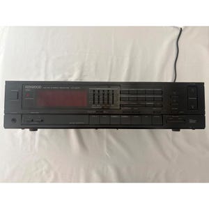 May include: A black Kenwood AM-FM stereo receiver model KR-A51R featuring a digital display, a five-band graphic equalizer, multiple push-button input selectors, a headphone jack, and a large vertical volume control rocker switch on the right side.