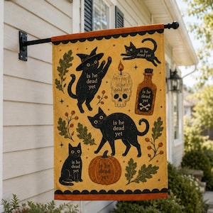 May include: A rectangular garden flag with a mustard yellow background featuring black cats, a pumpkin, a skull candle, and a potion bottle. Each element includes the text "is he dead yet". The flag has orange scalloped borders at the top and bottom.