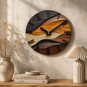 May include: A circular wall clock featuring a layered, wavy design made of wood in varying shades of black, dark brown, light brown, and cream. The clock has black hour and minute hands and black rectangular markers for the hour positions.