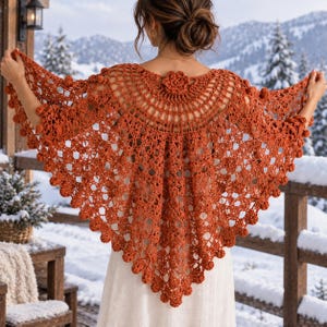May include: A burnt orange crochet shawl featuring an intricate openwork pattern with small bobble accents throughout the fabric. The shawl has a semi-circular neckline adorned with a central crochet flower detail and a pointed hemline.