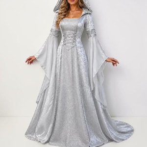 May include: A floor-length silver dress featuring a hood, long flared bell sleeves, and a lace-up corset-style bodice. The fabric has a subtle tonal damask pattern throughout, with a fitted waist that flows into a full, floor-sweeping skirt.