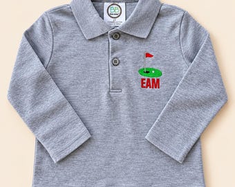 Könnte beinhalten: Ein langärmeliges Poloshirt in Grau meliert mit Kragen und drei Knöpfen. Auf der Brust befindet sich ein gesticktes grünes Golf-Putting-Green mit roter Fahne und weißem Golfball, darunter der rote Stickschriftzug EAM unter dem Motiv.