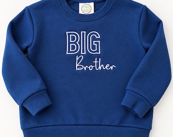 Könnte beinhalten: Ein langärmeliges königsblaues Sweatshirt mit geripptem Rundhalsausschnitt, Bündchen und Saum. Auf der Vorderseite befindet sich der Text BIG in einer fetten, weiß umrandeten Blockschrift über dem Wort Brother in weißer Schreibschrift.