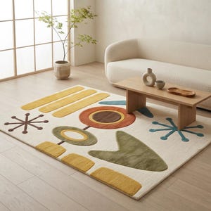 Può includere: Un tappeto rettangolare con base bianco sporco e un motivo trapuntato di forme geometriche in giallo senape, verde oliva, arancione bruciato, marrone e verde acqua, inclusi motivi a stella, cerchi e forme organiche astratte.