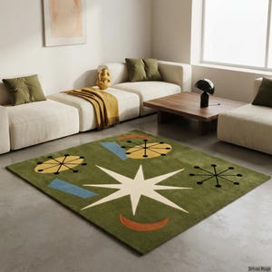 May include: A rectangular area rug featuring a deep olive green background with a large central cream-colored star, yellow oval shapes with black spokes, light blue rectangles, and a curved orange crescent shape arranged in a geometric pattern.
