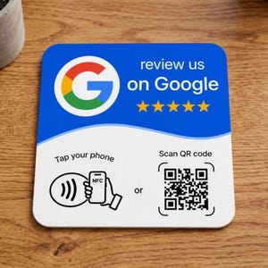 May include: A square sign with a blue top section featuring the Google logo, the text review us on Google, and five yellow stars. The white bottom section displays an NFC tap icon with the text Tap your phone and a QR code with Scan QR code.