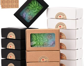 May include: A collection of rectangular gift boxes in black, white, and brown kraft paper, each featuring a clear window revealing a green succulent and dragonfly soap. Each box is sealed with a round sticker labeled Handmade With Love.