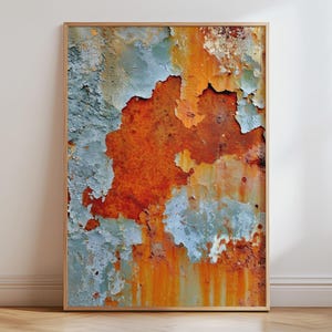 May include: A rectangular wall art print in a light wood frame featuring a high-resolution photograph of a weathered metal surface. The image displays layers of peeling light blue paint revealing a vibrant, textured orange rust underneath.