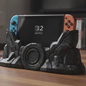 May include: A Nintendo Switch console with a blue left controller and an orange right controller, docked in a dark gray, textured rock-shaped stand. The screen displays the Nintendo Switch logo and the number 2 in a white font on a black background.