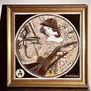 May include: A square framed art piece featuring a circular illustration of a person surrounded by tree branches. The artwork uses brown, cream, and gold tones. The letter A is in a small circle in the bottom left, and the word Autumn is in the bottom right.