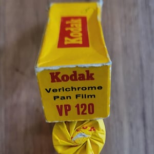 May include: A yellow box of Kodak Verichrome Pan Film VP 120. The box is yellow with red lettering.