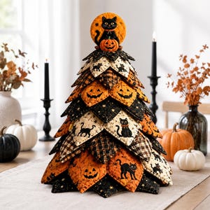 May include: A decorative fabric tree featuring a quilted design with Halloween motifs including black cats, orange pumpkins, and stars. The tree is constructed from layered, triangular fabric pieces in black, orange, and cream, topped with a circular cat ornament.