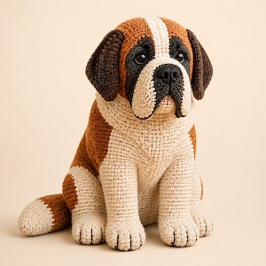May include: A handcrafted crochet Saint Bernard dog figurine featuring a tri-colour pattern of brown, white, and black yarn. The plush toy has dark brown ears, a white chest and muzzle, and black accents around the eyes and nose with dark plastic eyes.