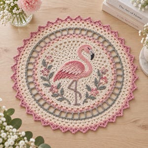 Könnte beinhalten: Eine runde Häkeldeckchen mit einem zentralen Flamingo-Motiv, umgeben von kleinen Blumen- und Blattmustern. Das Design kombiniert cremefarbene, zartrosa und graue Garne mit einem gewellten Rand und einer komplexen, durchbrochenen Bordüre.
