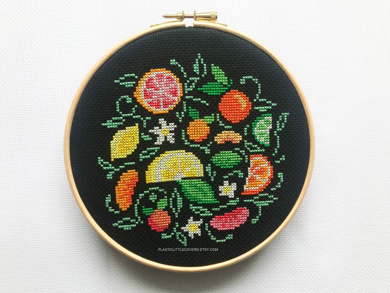 May include: A black embroidery hoop with a colorful cross-stitch design of lemons, oranges, and limes with green leaves and white flowers. The text "plasticuttlecove.etsy.com" is at the bottom of the hoop.