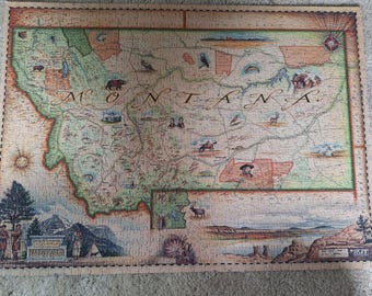 Könnte beinhalten: Ein rechteckiges Puzzle mit einer illustrierten Landkarte von Montana im Vintage-Stil. Die Karte zeigt die Staatsgrenzen, geografische Merkmale und verschiedene Tierillustrationen. Das Wort MONTANA ist in großer, eleganter Schreibschrift in der Mitte gedruckt.