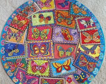 Könnte beinhalten: Ein kreisförmiges Puzzle mit einer Collage aus rechteckigen Feldern, die jeweils eine bunte Schmetterlingsillustration zeigen. Die Schmetterlinge sind in leuchtenden Rot-, Gelb-, Blau-, Lila- und Rosatönen gehalten und von einem blauen Rand umgeben.