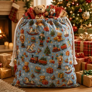 May include: A light blue drawstring gift sack featuring a repeating pattern of nutcrackers, teddy bears, rocking horses, toy trains, sailboats, and wrapped presents, with white rope handles and a teddy bear and nutcracker peeking out the top.