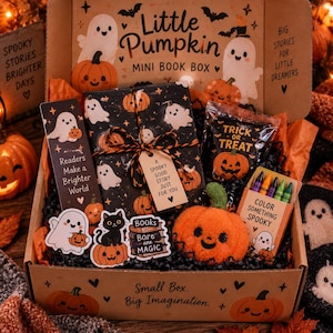 May include: A Little Pumpkin Mini Book Box containing a wrapped book, a bookmark with the text Readers Make a Brighter World, a Trick or Treat bag, a plush orange pumpkin, a box of crayons, and stickers featuring ghosts, a cat, and pumpkins.